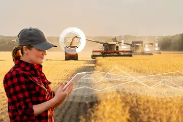 female farmer standing in a field using a laptop